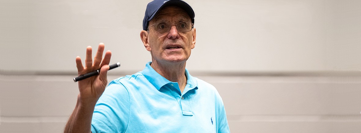 Photo of Perry Zirkel, lecturing in a blue baseball cap, blue collared shirt, holding a pen.